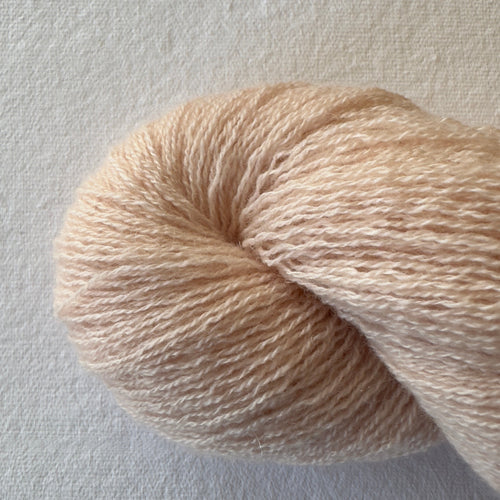 Close-up of lace weight reclaimed cashmere yarn in Apricot Jam, a pastel peach tone with subtle halo.
