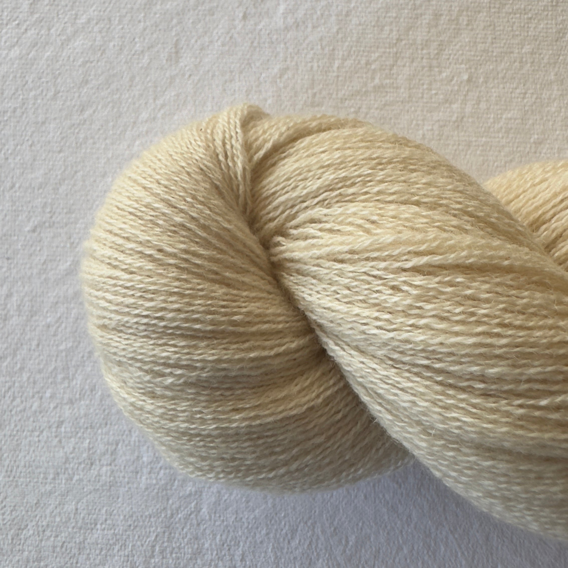 Close-up of delicate lace weight reclaimed cashmere yarn in Raw Honey, a buttery neutral cream tone with soft halo.